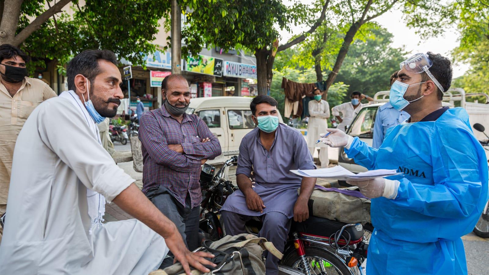 Photo 4 Photo of a doctor speaking with a small group of workers on a street in Pakistan.