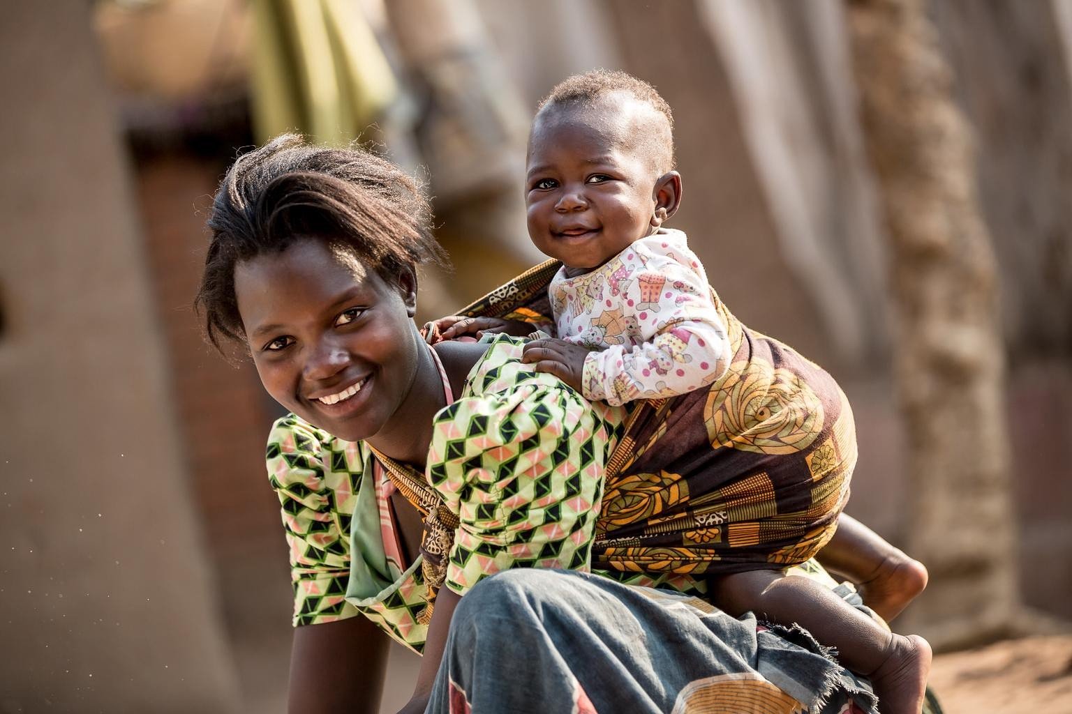 Woman and child Malawi An African woman carrying her baby on her back, both smiling for the camera